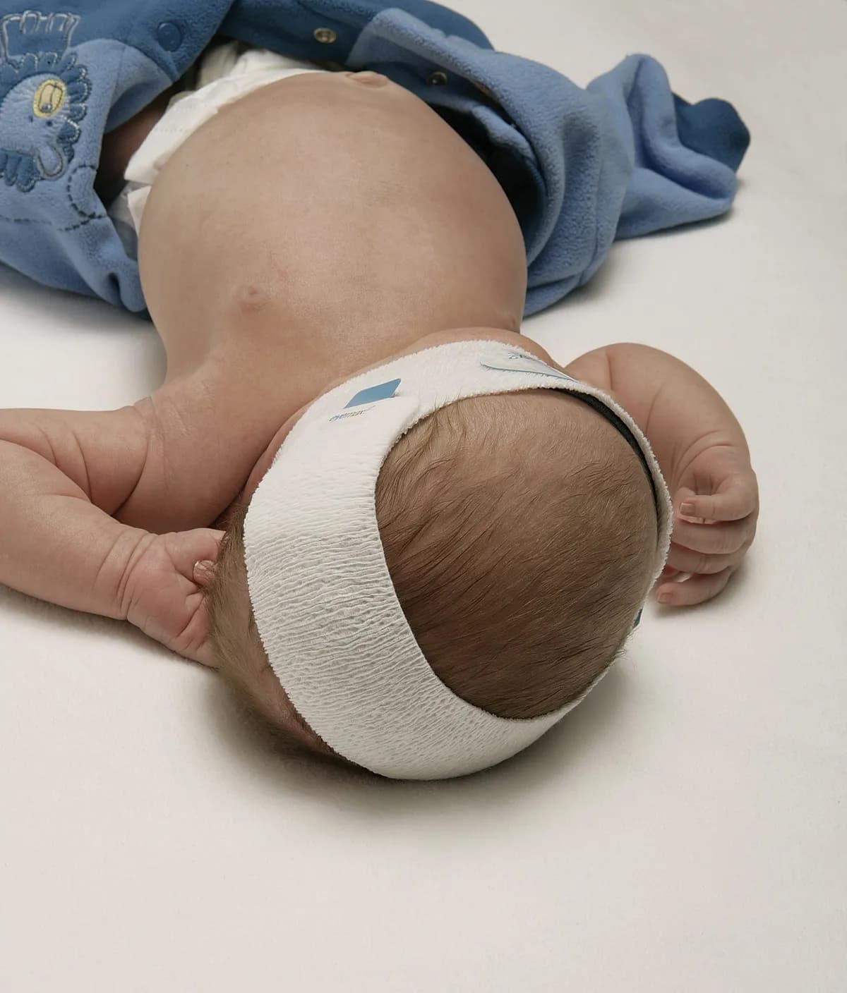 Vedere din spate a capului unui nou-născut cu EyeMax 2: banda dintr-o singură bucată înconjoară capul, cu închidere cu arici